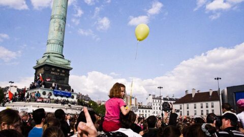 Crowd gathered in a Paris square under a blue sky