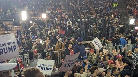 Crowd holding signs at a Donald Trump campaign rally in an arena