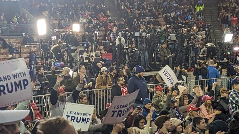 Crowd holding signs at a Donald Trump campaign rally in an arena